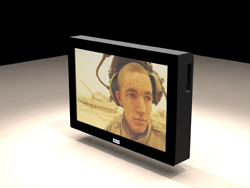 A black rectangular monitor displaying a close-up portrait of a man wearing a headset in a desert setting.