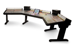 A wide, black professional music production desk with a mixing console and two studio monitors.