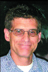 A man with short dark hair and glasses smiling at the camera.
