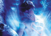 A man bathed in bright blue light with a glowing Superman shield on his chest.