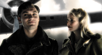 A man in a dark jacket and a blonde woman in a coat stand before a propeller-driven aircraft.