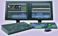 Two computer monitors displaying video editing software next to a control surface and keyboard.