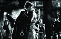 Black and white shot of a central couple embracing with other people standing in the background.