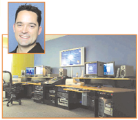 A man smiling in a portrait inset over a room filled with computer monitors, speakers, and workstations.