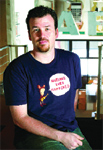 A man with short dark hair and a goatee wearing a navy blue t-shirt with a graphic on it.