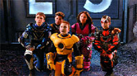 Five children in various colorful, armored superhero costumes posing together in a group.