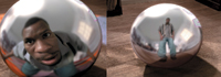 A close-up and a wide shot of a man's reflection in a shiny, metallic sphere on a textured surface.