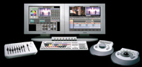 Dual monitors displaying video editing software surrounded by various control panels and joysticks.