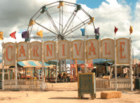 A large sign reading 'CARNIVALÈ' in front of a Ferris wheel at an amusement park under a cloudy sky.