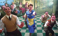 A group of people in mid-century attire dancing joyfully on a green and white checkered floor.