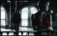A woman in a red dress looks away in the foreground, with a man standing before bright arched windows behind her.