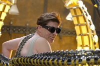 A man wearing dark goggles and a tank top with large mechanical tentacles surrounding him.