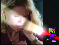 A woman squinting while looking at a bright light beam coming from a small colorful character.