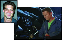 A portrait of a smiling man next to a man in blue coveralls working on a dark vehicle.
