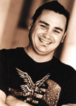 A smiling man with dark hair wearing a black t-shirt with an eagle graphic.