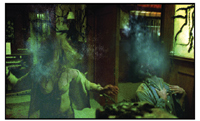 Two people in a dark room are enveloped in swirling blue smoke and mist.