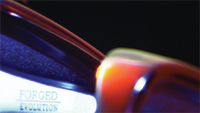 Close-up of a dark, curved metallic surface with the words FORGED EVOLUTION printed in blue.