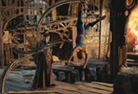 A person in blue performs a handstand in a derelict, industrial-style building near a figure in dark robes.