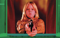 A young girl with blonde hair aims a handgun directly at the viewer from behind red curtains.