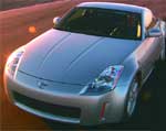 A silver two-door sports car parked on a road during sunset.