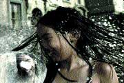 A woman with long dark hair is captured mid-motion amidst a large splash of water.