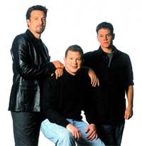 Three men in dark clothing posing together against a white background.