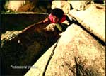 A person wearing a red shirt lies between large, light-colored rocks.