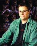 A man with glasses wearing a green button-down shirt over a black t-shirt.