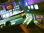 A control room filled with glowing monitors, video switchers, and technical equipment under blue lighting.