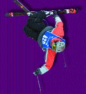 A skier in a red and grey jacket and black pants performs a mid-air flip with skis extended.