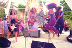 A band of musicians playing instruments and jumping on an outdoor stage during a performance.