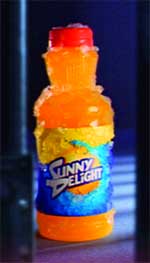 A frozen, ice-covered bottle of orange Sunny Delight soda against a dark blue background.