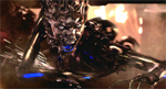 A dark, metallic humanoid figure with glowing eyes and blue light accents against a warm background.