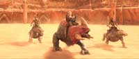 Three figures riding large, quadrupedal creatures in a sandy, sunlit arena.