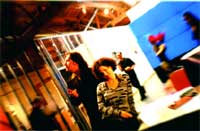 Several people stand in a room with bright white and blue lighting and reflective surfaces.