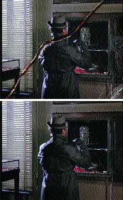 A person in a dark coat stands in a dimly lit room holding a long, thin object.