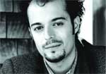 Black and white close-up portrait of a man with dark hair and a goatee looking at the camera.