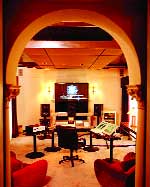A home theater room viewed through a large archway, featuring a large screen and audio equipment.