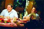 Three men sitting at a table outdoors, laughing and talking.