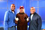 Three men standing side by side and smiling in front of a blue curtain backdrop.