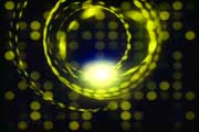 Glowing yellow light trails forming a spiral shape against a dark background with blurred bokeh dots.