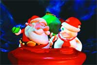 A Santa Claus figurine and a snowman figurine standing together on a red base against a dark blue background.