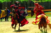 Two knights in red and black armor jousting on horseback in an arena.