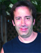 A man with dark hair and a dark blue shirt smiling at the camera.
