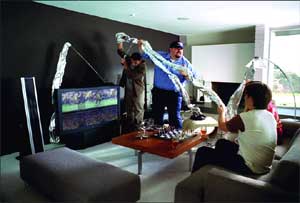 People in a living room holding up a large, clear plastic sheet near a television.