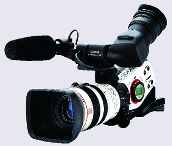 A professional video camera with a large lens, a black microphone, and an eyepiece against a gray background.