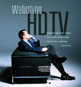 A man in a dark suit reclines on a black leather ottoman against a gray background with large text.