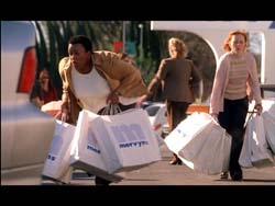 Two women walk outdoors carrying several large white shopping bags.