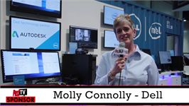 A woman smiles while holding a microphone in front of computer monitors and Dell branding.