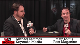 Two men in suits sit at a table with microphones during a televised discussion.